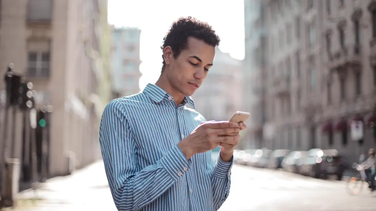 Man on a city street checking his phone to find a business nearby