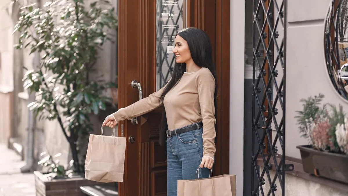 Smiling customer leaving a shop with shopping bags