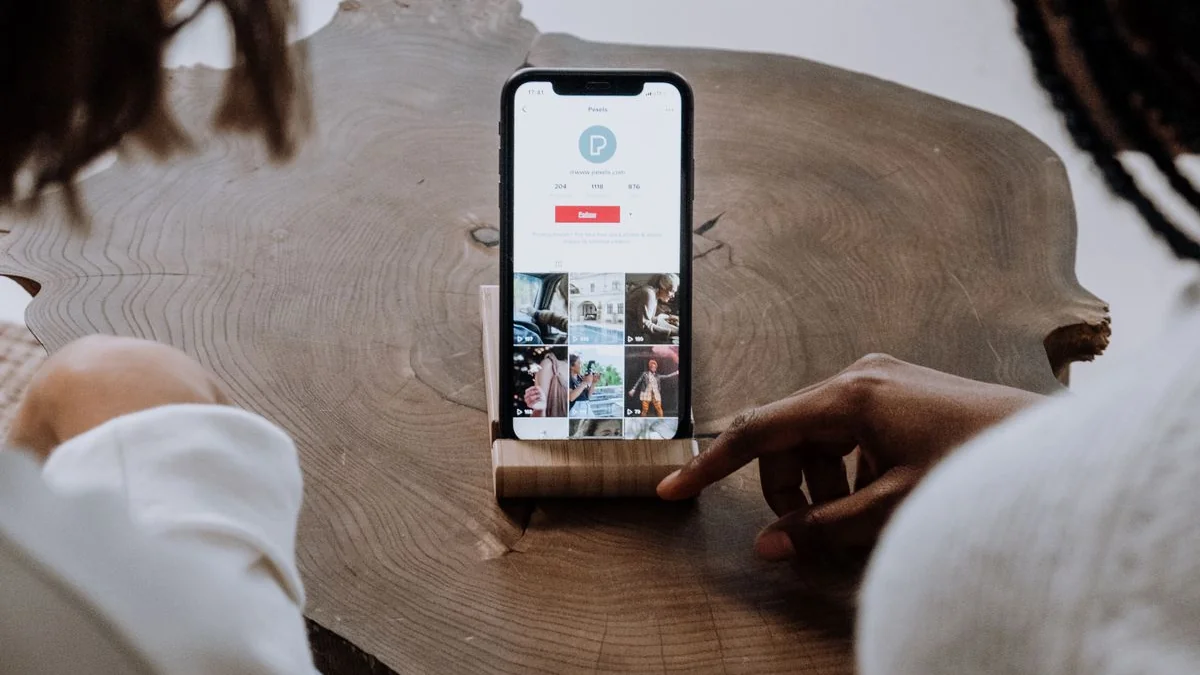 Phone on a wooden table showing a photo profile grid