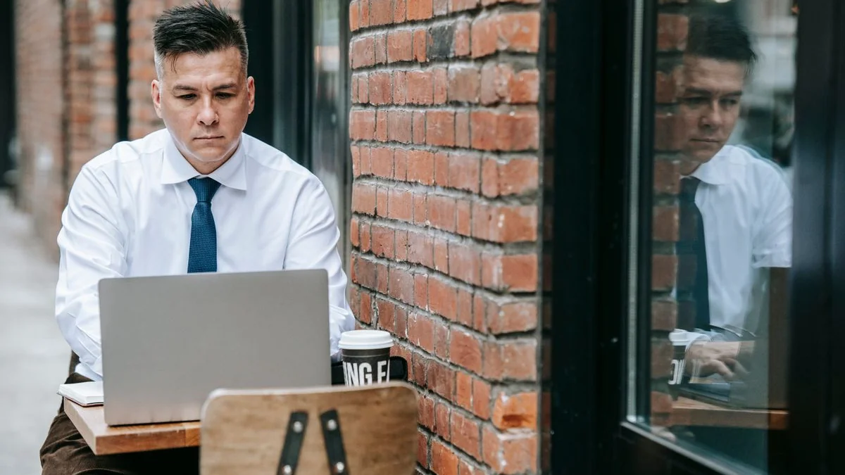Business owner working on a laptop outside his shop