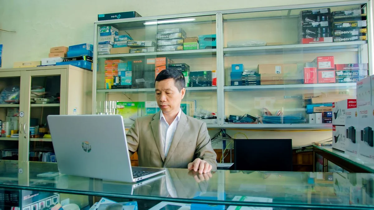 Shop owner working on a laptop behind a shop counter
