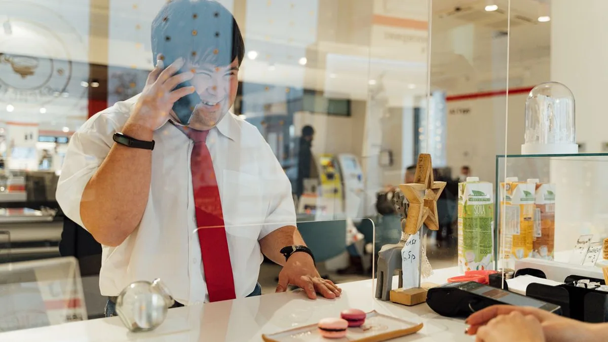 Cafe worker smiling while talking on the phone with a customer