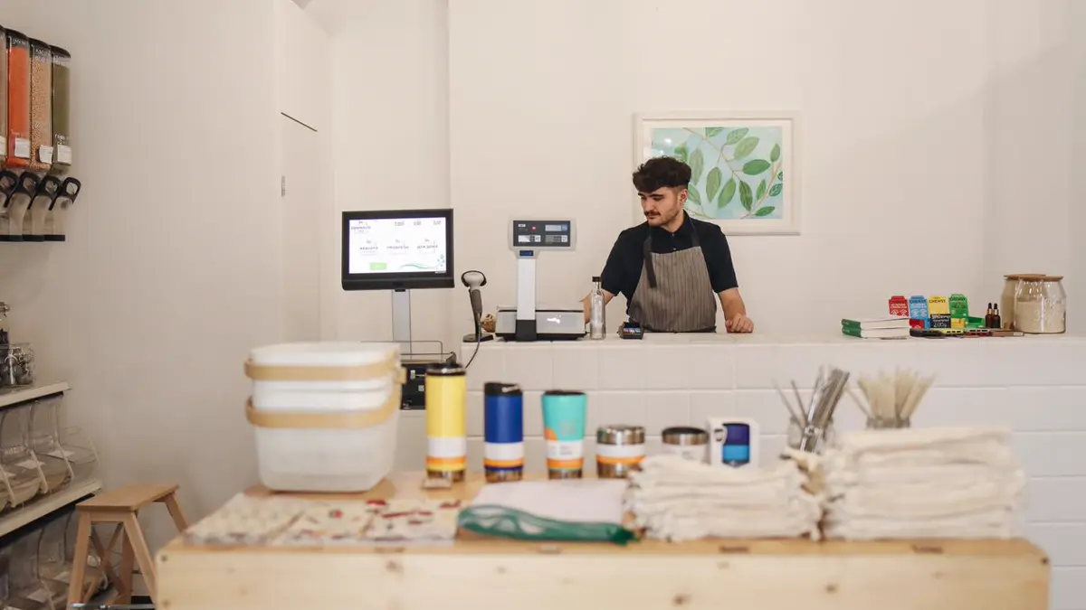 Young shopkeeper behind the counter of a bright modern shop