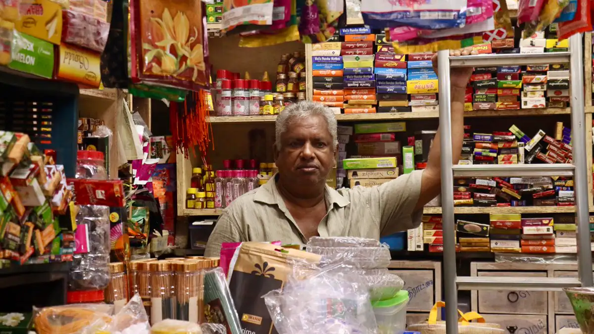 Shop owner standing inside his colourful local shop