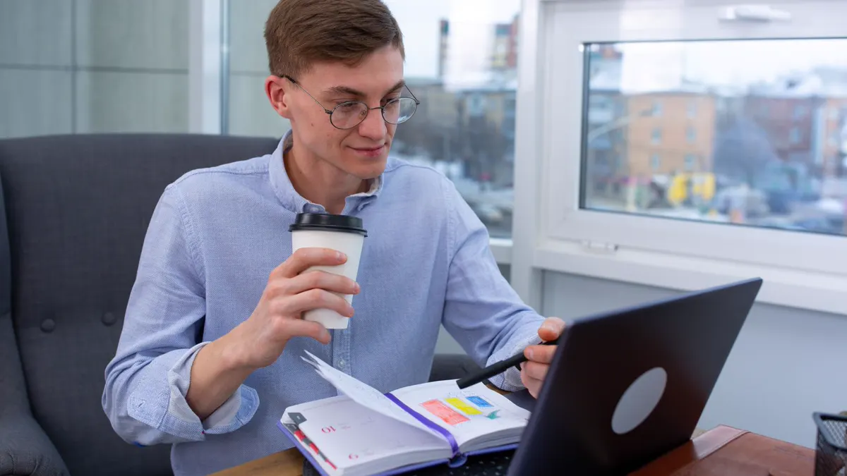 Young professional working on a laptop with coffee and a planner